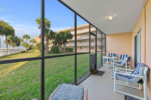 Gone Coastal l Ground Floor Condo l Steps to Beach في Anastasia Island: بلكونه فيها طاوله وكراسي ومبنى
