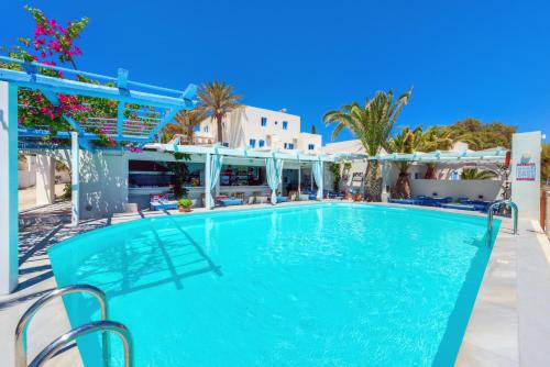 a large swimming pool in a resort with palm trees at Sigalas Beach Hotel in Kamari