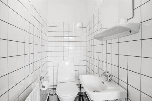 a white tiled bathroom with a toilet and a sink at JB200-Fjerritslev-Udklitvej-168 in Fjerritslev