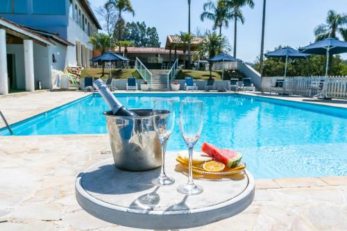 エストレーマにあるHotel Extrema Clubのプールの横に置かれたワイングラスとフルーツの載ったトレイ