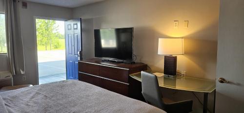 a bedroom with a bed and a desk with a television at Sunrise Inn in Eastman