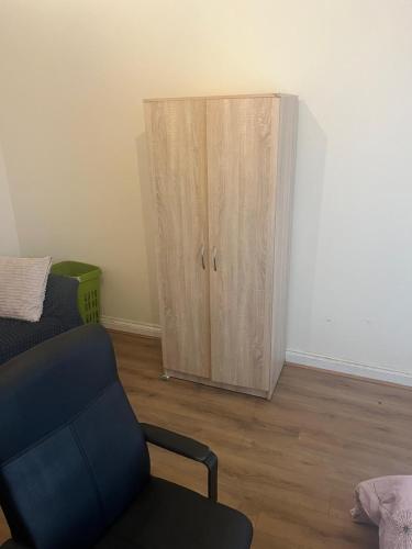 a cabinet in a living room with a couch and a chair at double room in wolverhampton in Wolverhampton