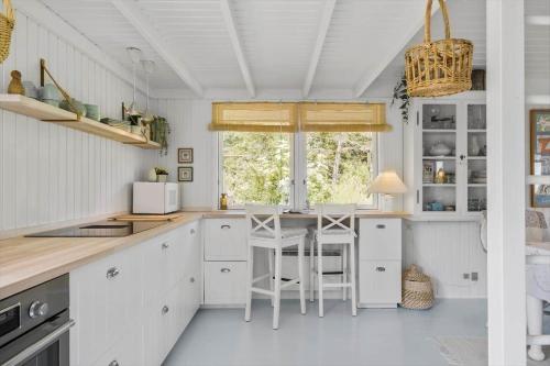 a kitchen with white cabinets and a counter with stools at JB401-Brovst-Solsortevej-1 in Tranum