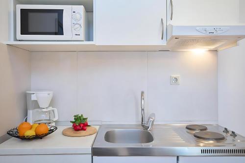 a white kitchen with a sink and a microwave at Festa Apartments & Rooms in Dubrovnik