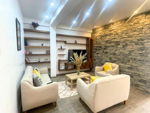 a living room with two couches and a stone wall at Rural Retreat with Charming Patio 2 Bedrooms in Urubamba