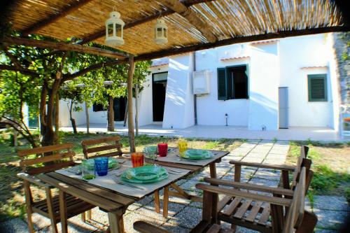 a picnic table under a pergola with two chairs at Montammare Casa Di Charme in Tramonti