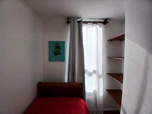 une chambre avec une fenêtre, un lit rouge et une étagère dans l'établissement departamento cómodo y central, à Santiago