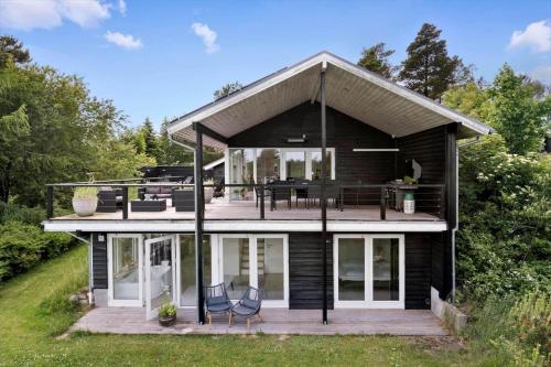 a black house with a deck and chairs at JB400-Brovst-Solsortevej-7 in Tranum