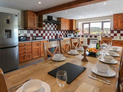 a kitchen with a wooden table with plates and wine glasses at Glanyrafon in Rhayader
