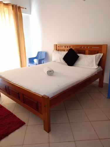 a wooden bed with white sheets and pillows on it at Blissspot linyonyi in Mombasa