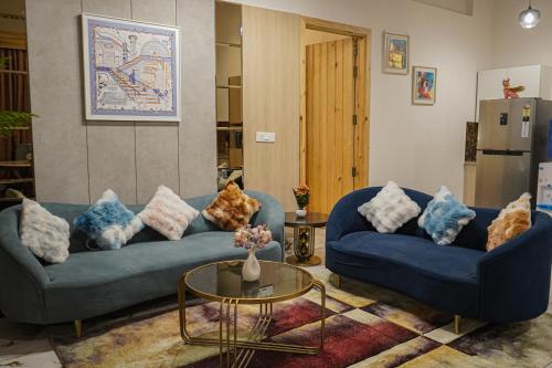 a living room with two blue couches and a table at The Uptown Kingdom Luxury Homestay in Mukteswar