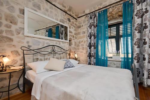 a bedroom with a white bed with blue curtains at Festa Apartments & Rooms in Dubrovnik