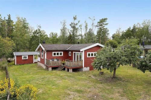 a red cabin in the woods with a yard at OST428-Moensteras-Ekeholmsvaegen-7 in Stora Oknö