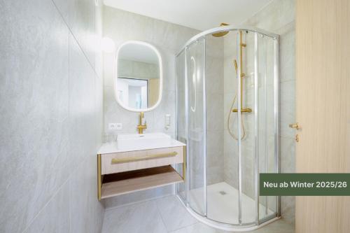 a bathroom with a shower and a sink and a mirror at Crystls Aparthotel in Flachau