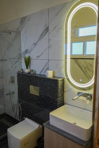 a bathroom with a sink and a mirror and a toilet at The Uptown Kingdom Luxury Homestay in Mukteswar