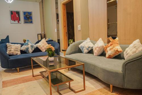 a living room with two couches and a glass table at The Uptown Kingdom Luxury Homestay in Mukteswar
