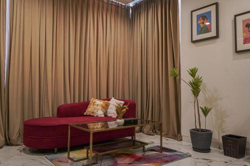 a living room with a red couch and a table at The Uptown Kingdom Luxury Homestay in Mukteswar