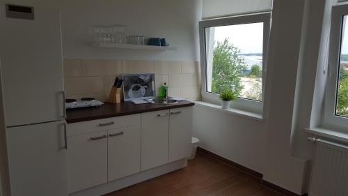 a white kitchen with a sink and a window at Pension Fischerjung in Rostock