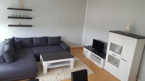 a living room with a blue couch and a tv at Pension Fischerjung in Rostock