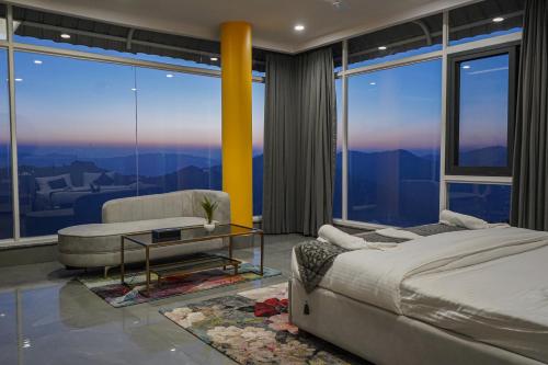 a bedroom with a bed and a table and windows at The Uptown Kingdom Luxury Homestay in Mukteswar