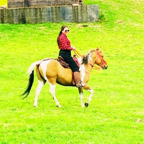 a woman riding a horse in a field at Glamping exclusivo de lujo en la montaña in Suesca