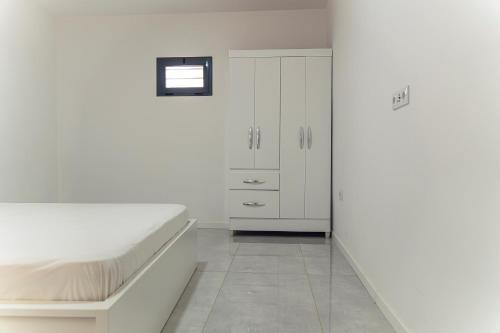 a white bedroom with a bed and a cabinet at 3-bdr apt 10-min walk laginha beach - LCGR in Mindelo