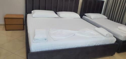 two beds with white sheets and a bow tie on them at Brusiano in Vlorë
