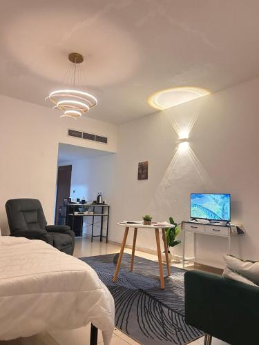 a bedroom with a bed and a table and a tv at GREEN SUITE ,Private Toilet ,Horizon Towers,AJMAN in Ajman