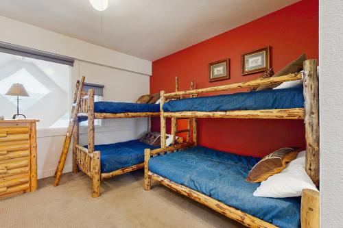 1 dormitorio con 2 literas y pared roja en Saddle Ridge Townhome I-5, en Big Sky