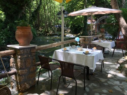 a table with chairs and an umbrella next to a river at Margaret's Island Hotel in Naousa Imathias