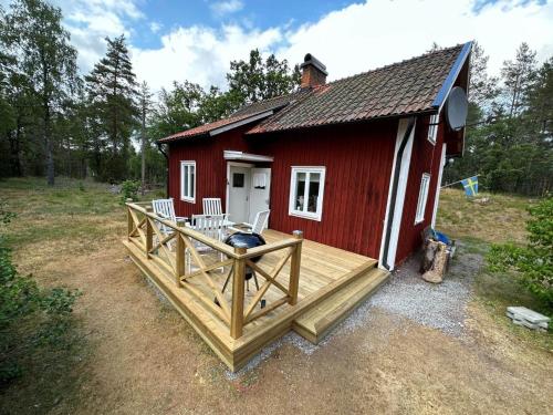 a red cabin with a deck and chairs on it at KAL159-Gullaskruv-Hetalaga-111 in Gullaskruv