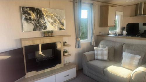 a living room with a fireplace and a chair at 8 birth Diamond rated Caravan, en-suite, with decking at Parkdean resorts, Southview holiday park in Winthorpe