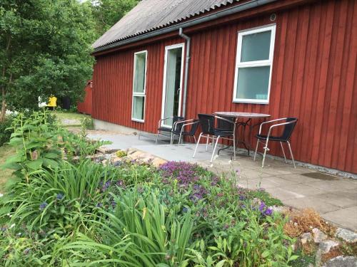 a patio with chairs and a table in front of a red building at SKA601-Roeke-Roeke-Algustorp-4198 in Röke