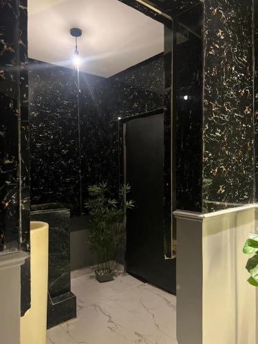 a bathroom with a black wall and a glass door at غرفة وصالة بالدرعية in Riyadh