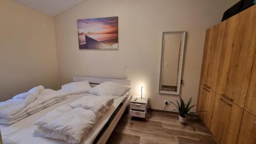 a bedroom with a bed with white sheets and a mirror at Ferienhaus Strandengel in Dorum Neufeld