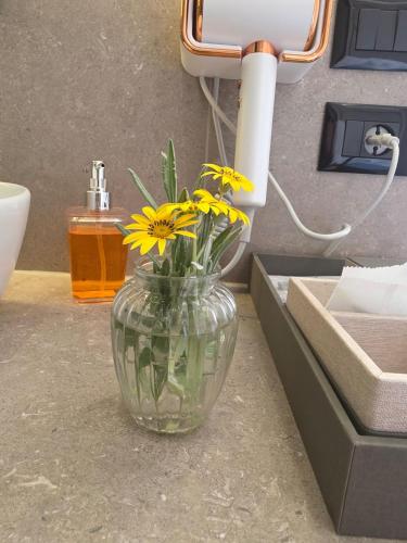 a glass vase with yellow flowers in it on a counter at Cape of Rodon Resort, Green Village in Draçi