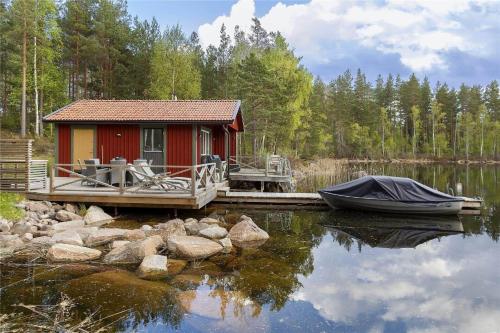 a red cabin on a dock with a boat on the water at OGO368-Boxholm-Tingkullanaes-6 in Blåvik