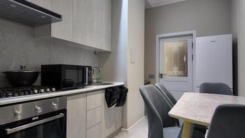 a kitchen with a stove and a table with chairs at Tashkent City Gardens Residence E7-4-25 in Tashkent