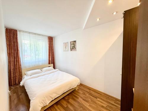 a bedroom with a white bed and a window at Berzei Astra - Rise Apartments in Braşov