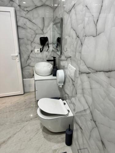 a bathroom with a toilet and a marble wall at London Restaurant Hotel in Kukës