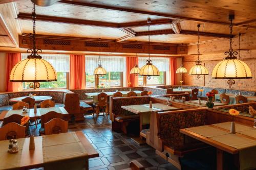 a restaurant with tables and chairs and pendant lights at Hotel-Landgasthof Ploss in Schönwald