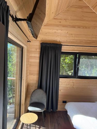 a bedroom with a bed and a chair and a window at Cabana Forest LakeView Potoci in Potoci