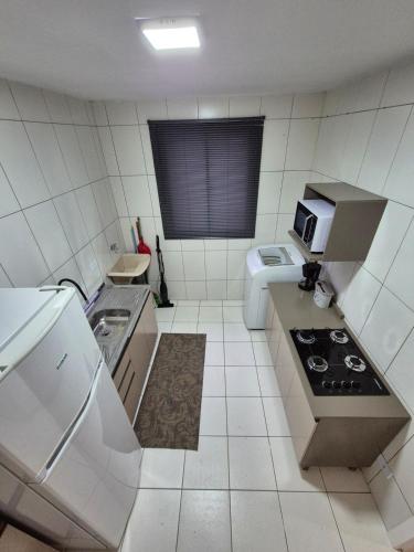 a small kitchen with a stove and a microwave at Apartamento de 1 quarto !! in Joinville
