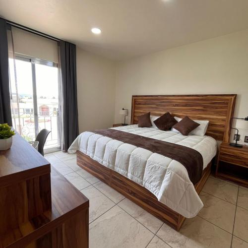 a bedroom with a large bed and a large window at Quinta Candela Hotel in Chignahuapan