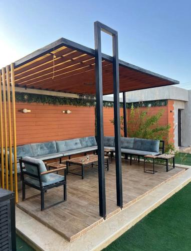 a pergola with benches and tables on a patio at شاليهات الأمواج in Qārā
