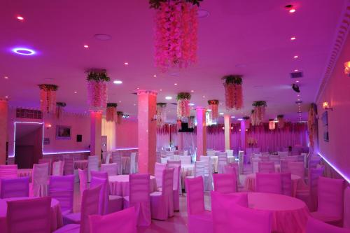 a room filled with white chairs and purple lighting at London Restaurant Hotel in Kukës
