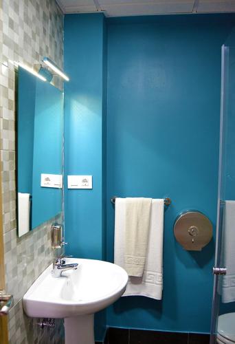 a bathroom with a sink and a blue wall at Hostal Restaurante Los Mellizos in Guarromán