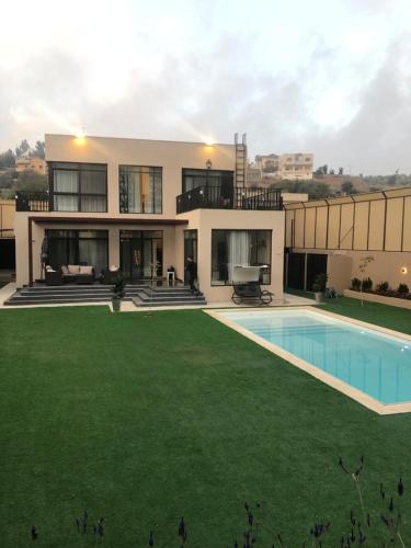 a large house with a large yard with a swimming pool at Villa27 in Amman