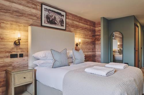 a bedroom with a large white bed and a mirror at The Barn Hotel in Meriden