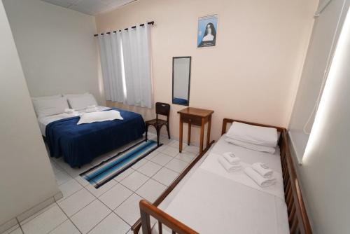a bedroom with two beds and a table and a mirror at Eventos & Hospedagem Sagrada Família in Sao Paulo